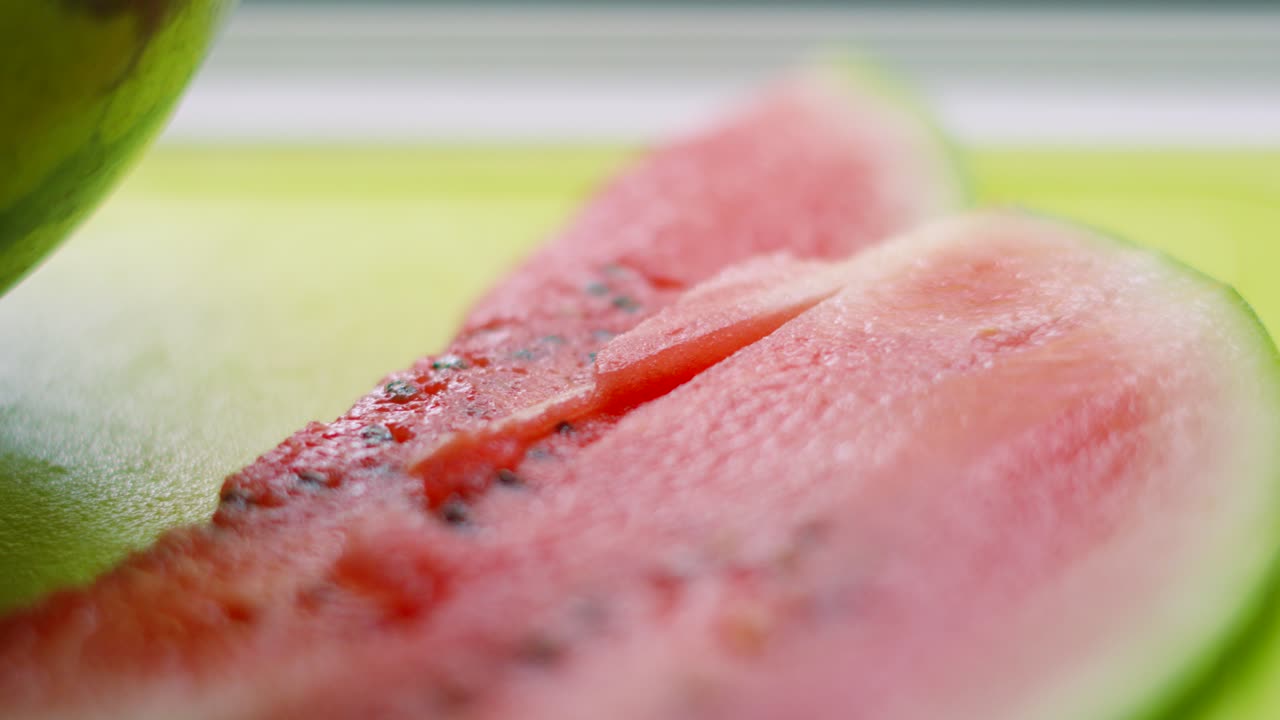 Slow Moving Shot Over Watermelon Slices on Chopping Board in Natural Light with Whole Fruit to the Left. Healthy Nutritious Food with Seeds