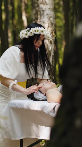 terapeuta mujer médico haciendo mujer relajante spa masaje facial con las manos al aire libre en el bosque