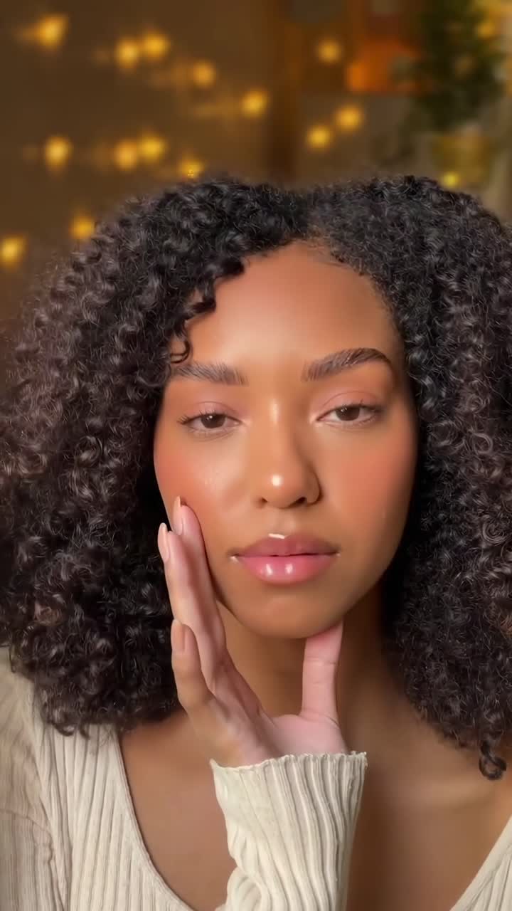 Close-up video of a woman with curly hair, soft lighting, and a gentle expression, front angle