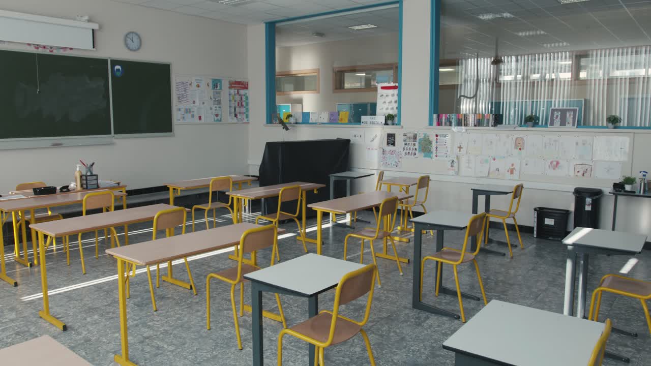 Empty classroom with chairs and desks with a chalkboard and drawings on the wall