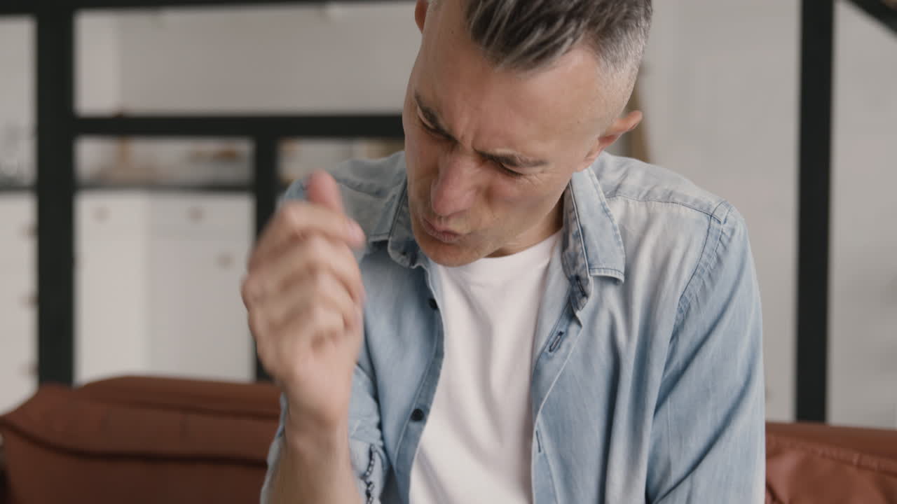 Middle Aged Man Having An Elbow Pain While Sitting On Sofa At Home