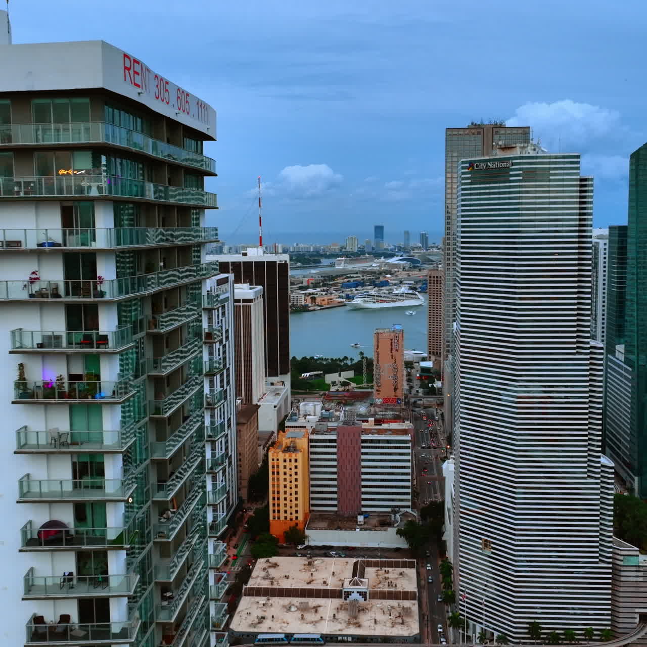 Drone flying along the building with glass balconies. Opening view to a harbor in Miami, Florida, USA.