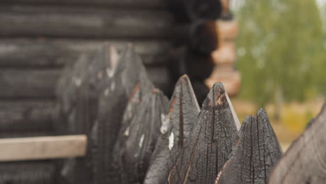 old fence made of wooden spikes near log house on sunny day