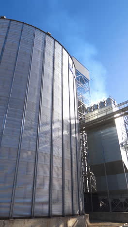 modern grain elevators at bright sunny day. large granary under blue sky. industrial manufacturing in the open air. vertical video