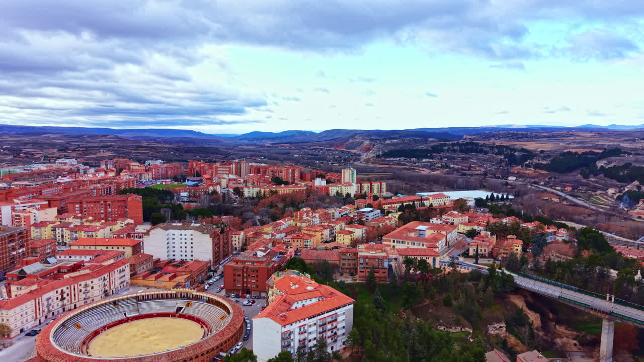 Udsigt over en by i Spanien med bygninger og en tyrefægterarena under en overskyet himmel om dagen