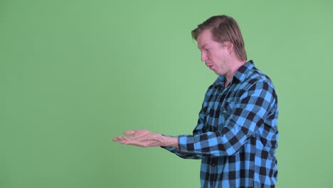 retrato de un hombre caucásico que se ve emocionado mientras trata de atrapar algo del espacio de copia disparado contra el fondo verde del estudio