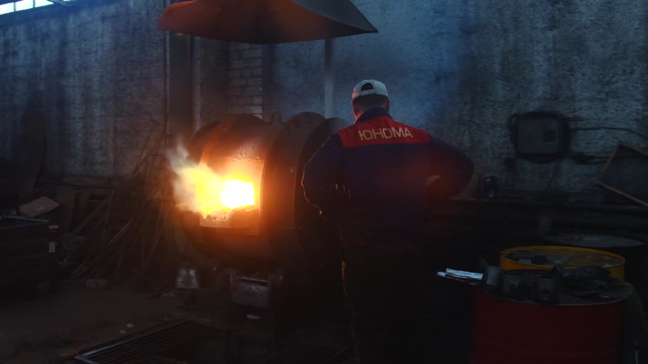 Worker observing a furnace in a metal workshop