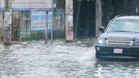 a black suv with flashing lights drives through a flooded street, followed by a man on a bicycle