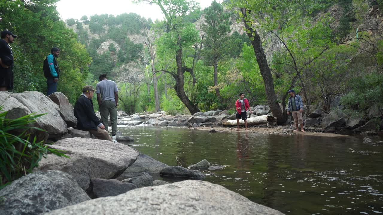 Friends laughing and skipping rocks by a creek in Boulder, Colorado during a summer day.