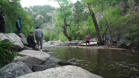 friends laughing and skipping rocks by a creek in boulder, colorado during a summer day.