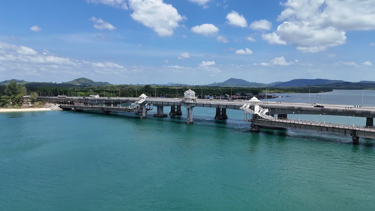 Drone footage captures Sarasin Bridge connecting Phuket to the mainland over turquoise waters under a bright sky