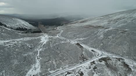 Kurvenreiche-Straße-Durch-Eine-Schneebedeckte-Landschaft,-Mit-Bewölktem-Himmel,-Luftaufnahme