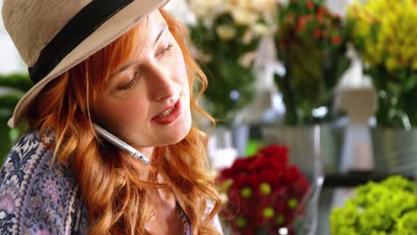 female florist talking on mobile phone while using digital tablet