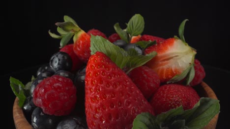 Makroansicht-Von-Waldfrüchten-In-Einer-Holzschale-Mit-Schwarzem-Hintergrund,-Erdbeeren,-Heidelbeeren-Und-Himbeeren,-Gesunde-Früchte,-4k-Aufnahme