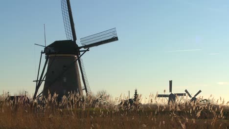 a slow pan across to windmills rising from the grass in holland