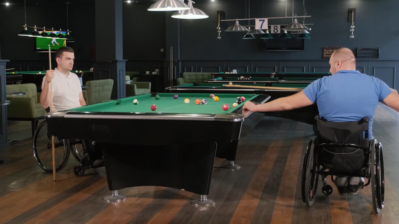Adult men with disabilities in a wheelchair play billiards in the club
