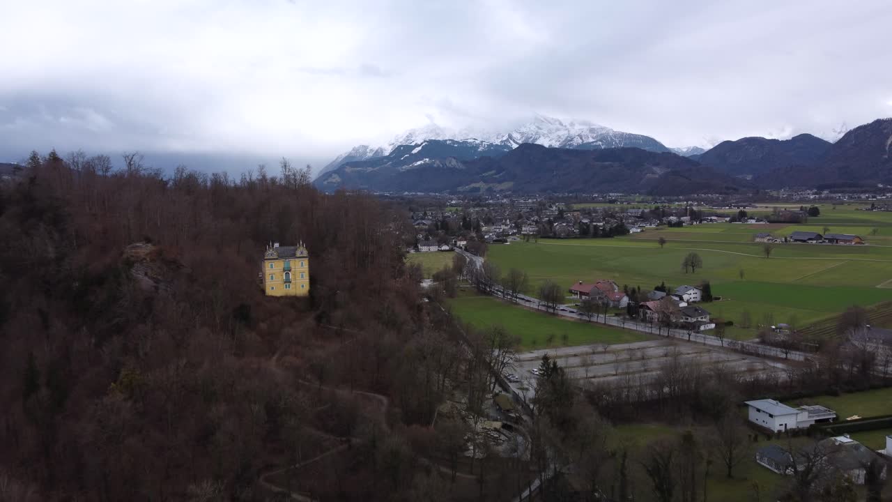 imágenes aéreas cinematográficas del campo de austria, que muestran un castillo del siglo xix en primer plano y montañas nevadas en el fondo