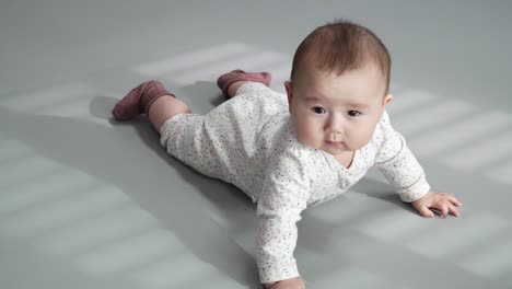 baby rolling over, looking at the camera smiling - full-body shot