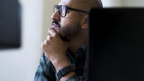 empresário cansado sentado no computador, reflexo da luz azul nos óculos