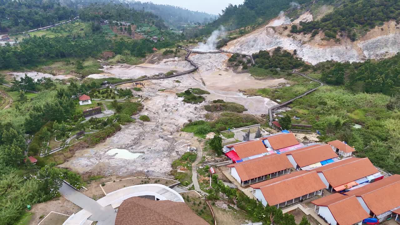 Aerial view of Kawah Sikidang, a volcanic crater in Dieng Plateau, Central Java, Indonesia, showing steaming sulfur vents and rugged geothermal terrain surrounded by green hills