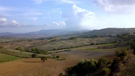 Italian-villas-on-farm-fields-in-the-Tuscan-countryside,-Aerial-approach-reveal-shot