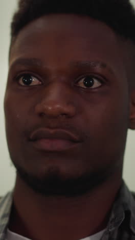 tranquil young african-american man in checkered shirt sits in living room closeup slow motion. attractive black guy model poses for camera