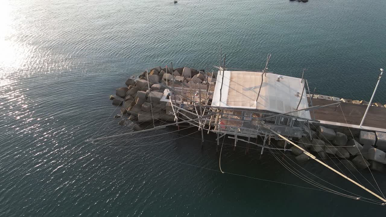 해가 지는 이탈리아 해안 에서 전통적 인  ⁇ 시 기계 인 트라부코 의 공중 해양 풍경