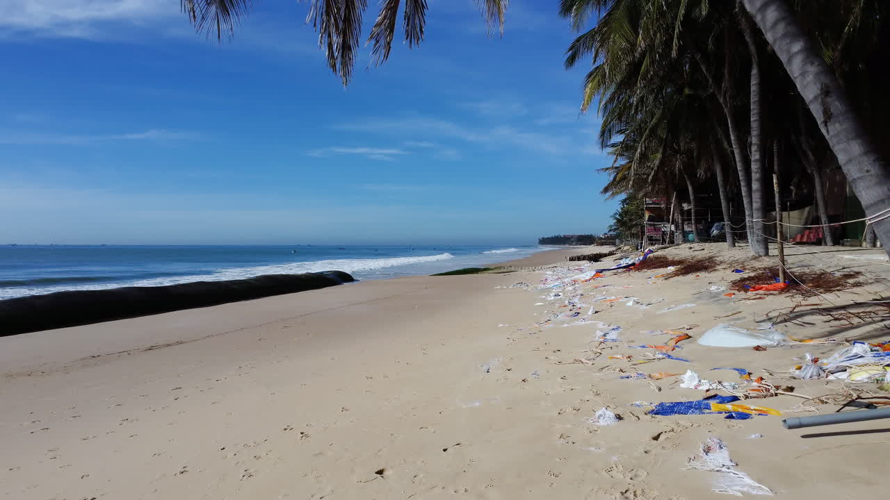 Geotubo en la playa de Mui Ne para combatir la erosión costera, con escombros marinos en la playa.