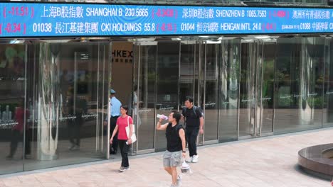 hong kong stock exchange: people walking past stock ticker