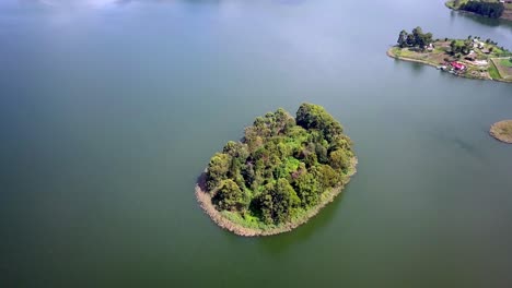 un dosel de árboles sobre una pequeña isla en medio de las plácidas aguas del lago bunyonyi, uganda, áfrica