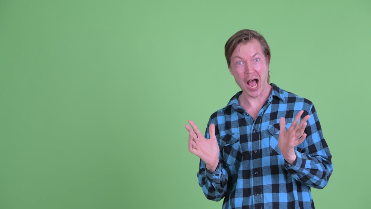 Portrait of Caucasian man touching copy space and looking excited and very happy shot against green studio background
