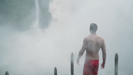 man looks around with massive bajos del toro waterfall crashing down in front