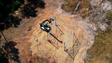 vista de pájaro de drones aéreos sobre los trabajadores que operan una grúa grande para instalar un poste eléctrico en un día soleado