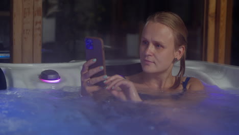 chica relajándose en el baño al aire libre con teléfono móvil