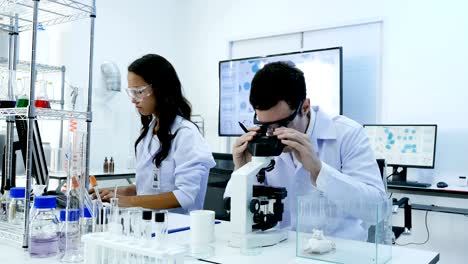 científicos o químicos que utilizan microscopios y otras tecnologías. científicos en equipo trabajando juntos en un laboratorio. resolución de 4k.