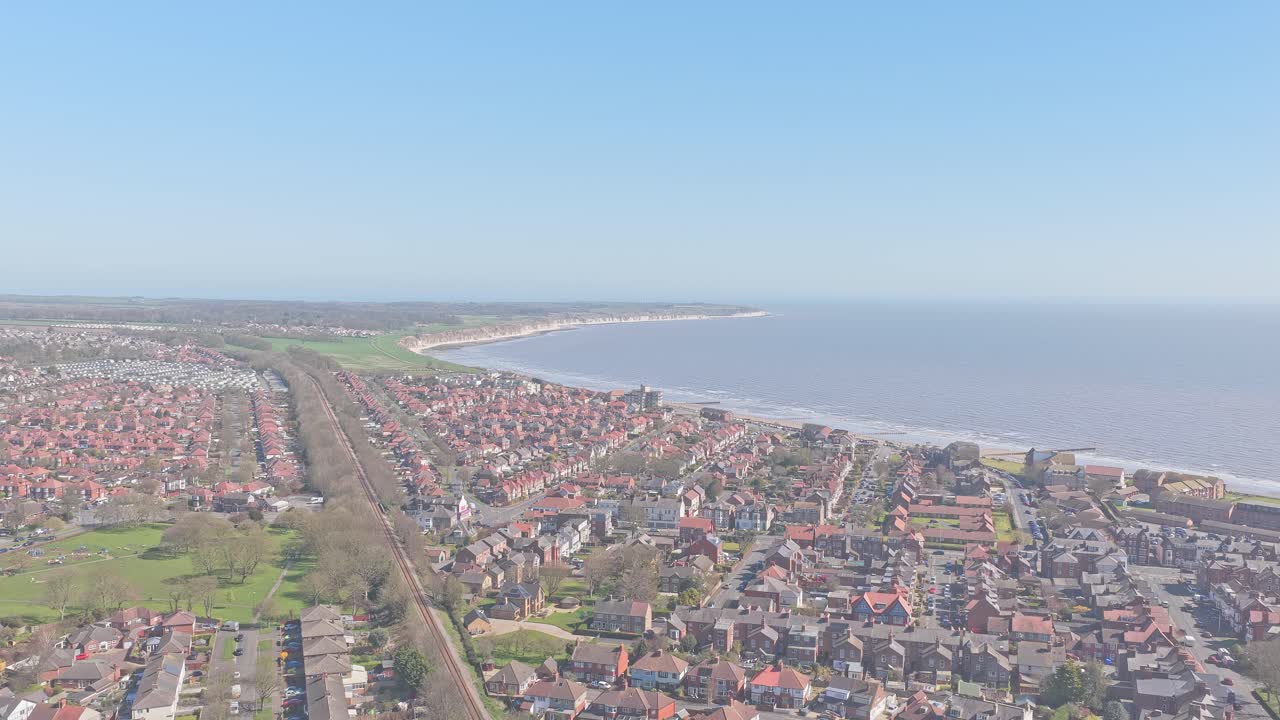 Bridlington, East Riding of Yorkshire, Yorkshire og Humber, England, Storbritannien med South Bay strand, boligområde og Hull Scarborough jernbanelinje, langsom fremadgående droneoptagelse