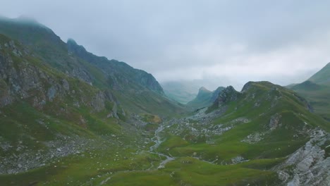 Circular-shot-of-misty-valley-with-river-in-mountain,-French-Alps