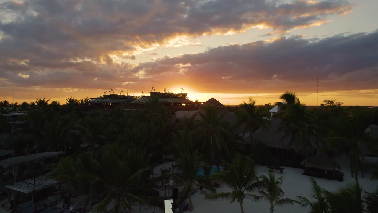 vista aérea de la puesta de sol detrás del paisaje de tulum en méxico mientras los turistas caminan por la playa de akiin