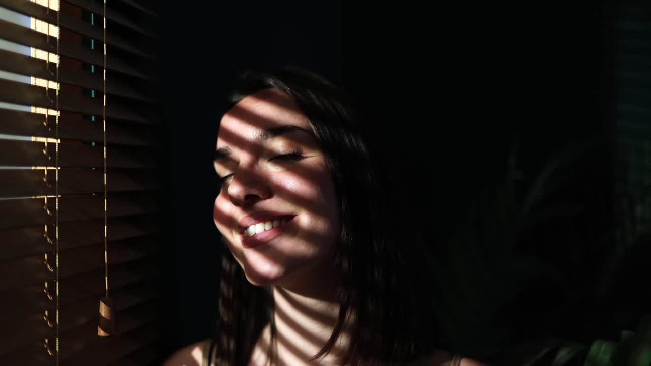 Young Woman Smiling in Sunlight with Blinds Shadows on Her Face