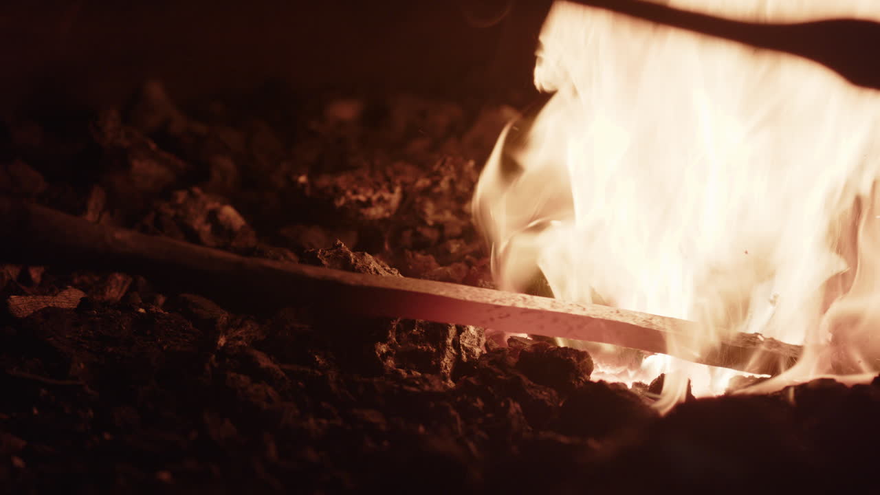 Red hot glowing iron in the blacksmith forge, as coals are adjusted around it