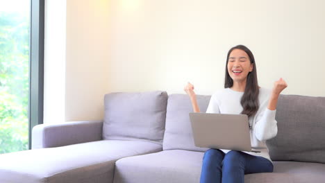 A-young-woman-working-on-her-laptop-reacts-in-triumph-as-she-completes-her-task