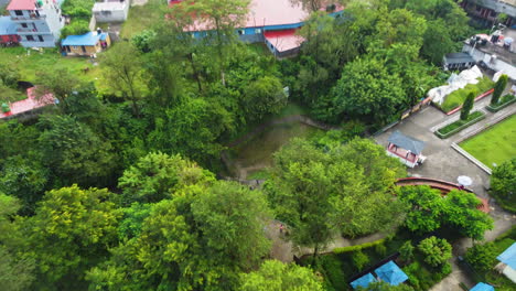 aerial overview tilt down above nature park and waterfall in pokhara nepal