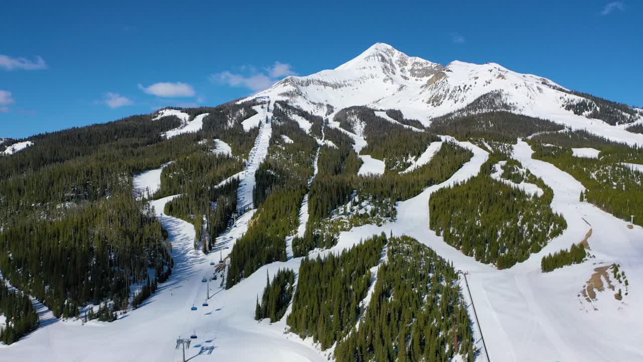 Skiers glide up on chair lifts and down icy trails at Big Sky, Montana, as a drone captures this snowy winter resort full of fresh powder, frosted pines, and breathtaking peaks