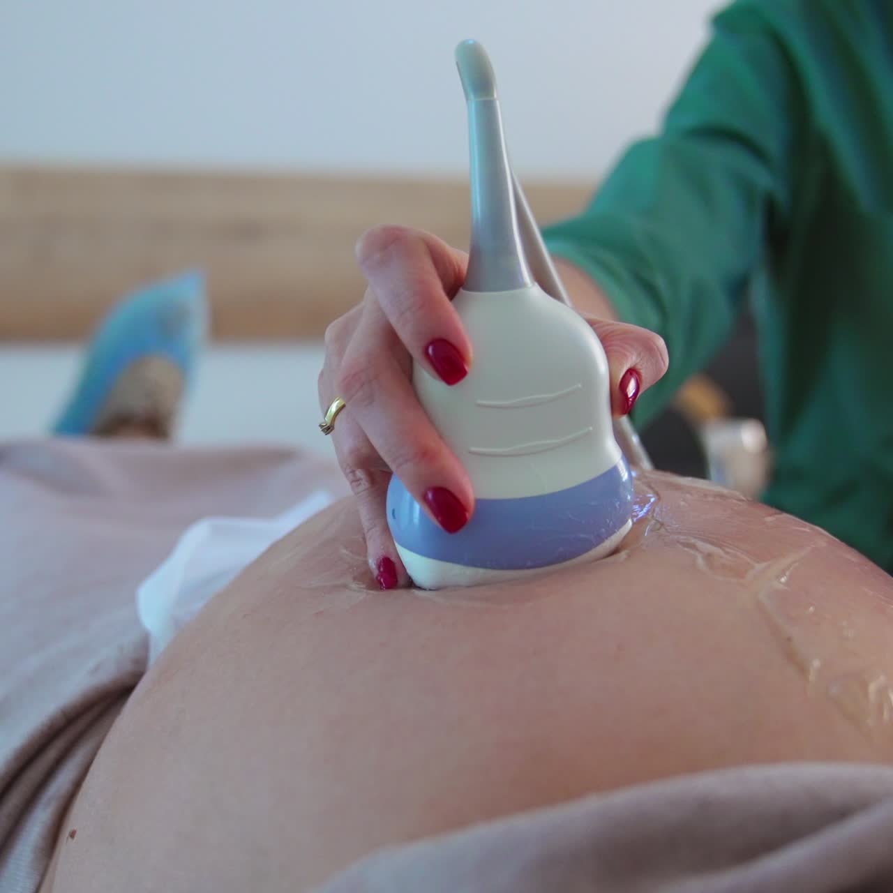 Pregnant woman with big stomach at doctor's examination. Doctor uses ultrasound device to see the baby development. Close up
