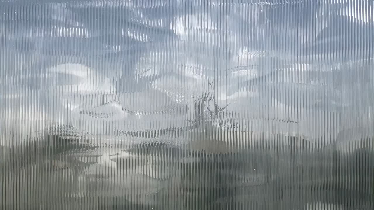 Showing ribbed translucent panel slowly blurring horizon view during day, sun behind cloud shifting