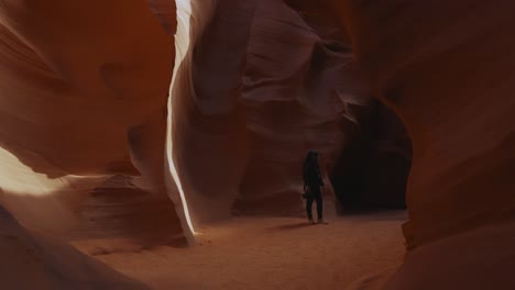 Young-woman-walking-in-Antelope-Canyon,-Arizona,-smooth-wavy-sandstone-walls