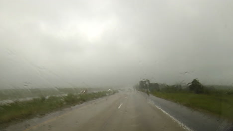 punto de vista de conducción viajando en condiciones de lluvia en la carretera con limpiadores de parabrisas