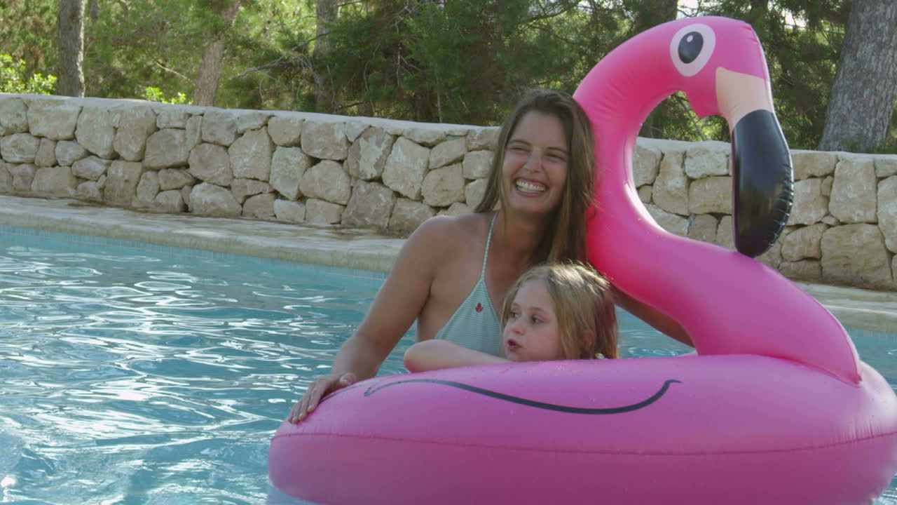 madre e hija en inflables en la piscina al aire libre