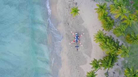 helicopter with striped rotor blades parked on unspoiled paradise beach resort at playa costa esmeralda, dominican republic