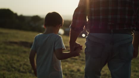 Rear-view-video-of-grandfather-and-grandson-walking-at-sunset